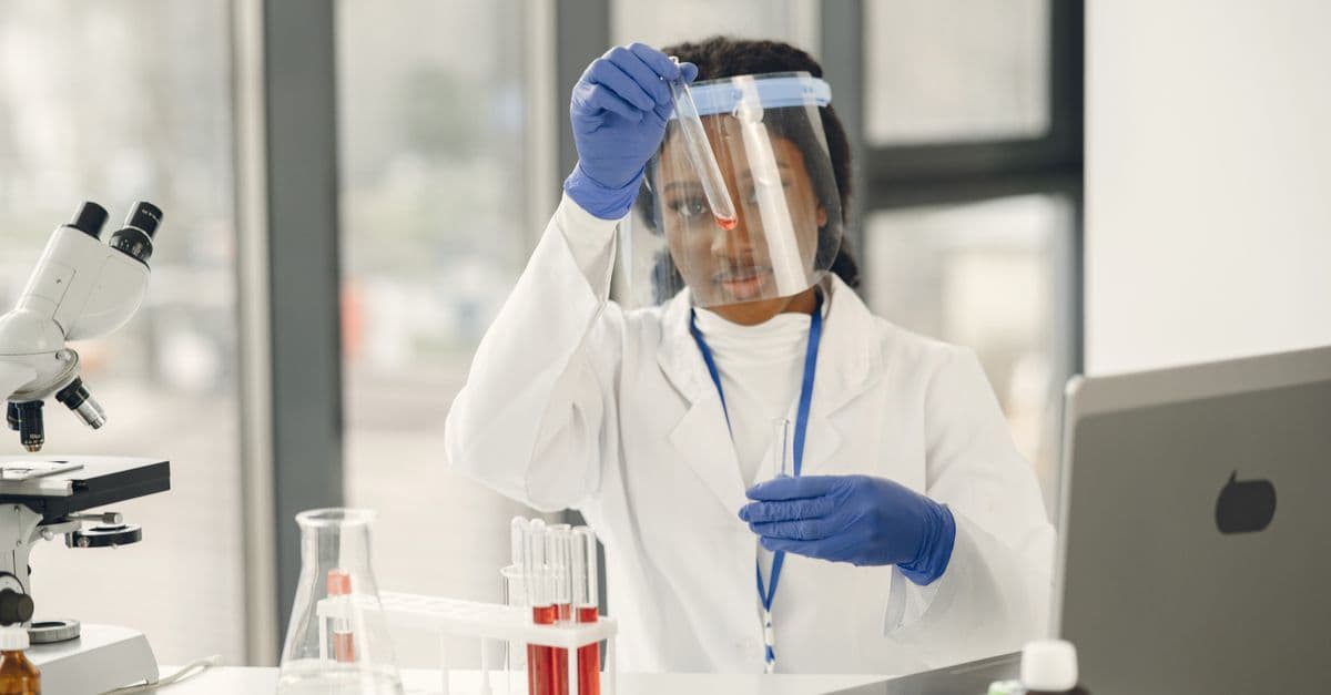 Female scientist working with test tubes and microscope in a laboratory.