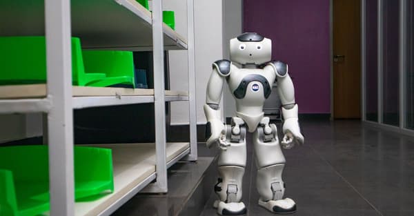 A humanoid robot standing in a modern corridor with shelves, representing futuristic technology.