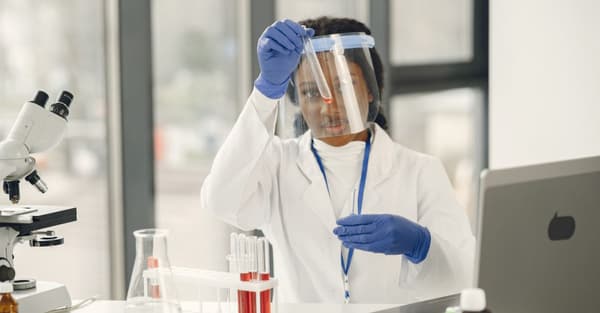 Female scientist working with test tubes and microscope in a laboratory.