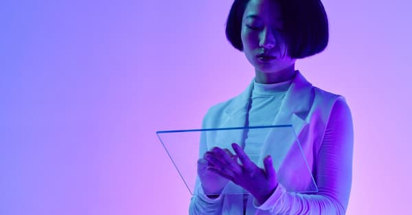 Woman interacts with a transparent digital screen in vibrant studio lighting.