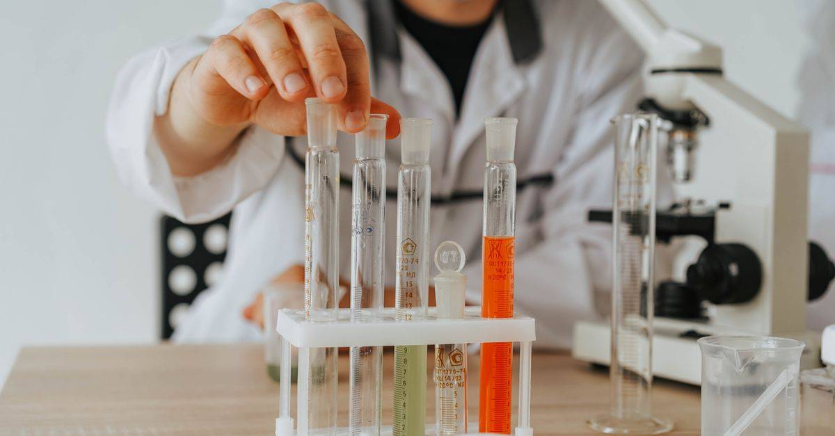 Scientist in lab coat conducting an experiment with test tubes and a microscope.
