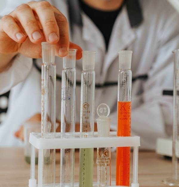 Scientist in lab coat conducting an experiment with test tubes and a microscope.