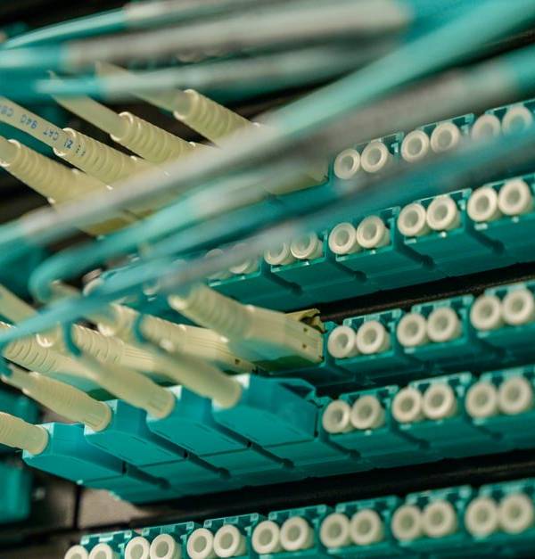 Detailed view of fiber optic cables connected to a server rack, showcasing modern technology.