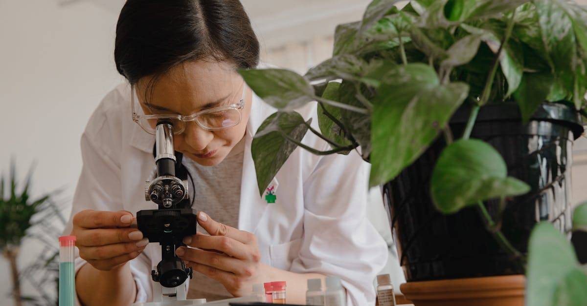 A scientist studies plant biology using a microscope in a lab setting.