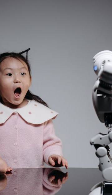 Two children fascinated by a toy robot, showcasing excitement and curiosity indoors.
