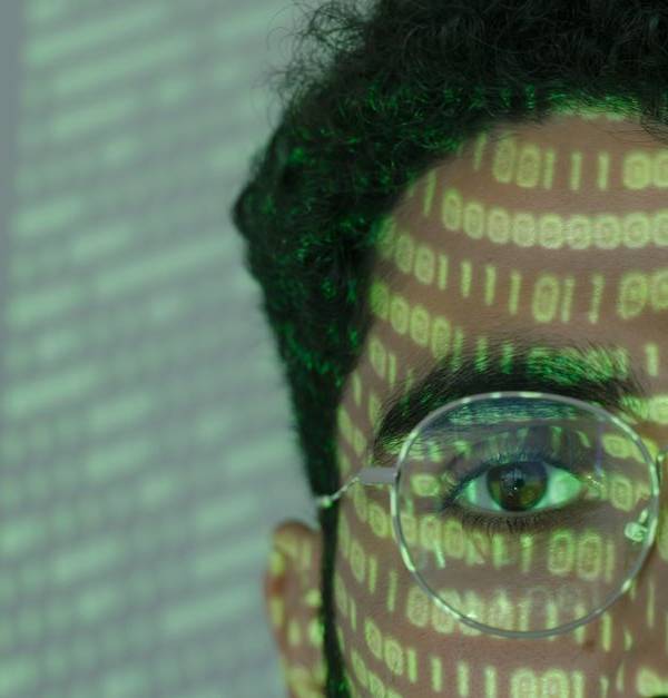 Close-up of a man with binary code projected on his face, symbolizing cybersecurity.