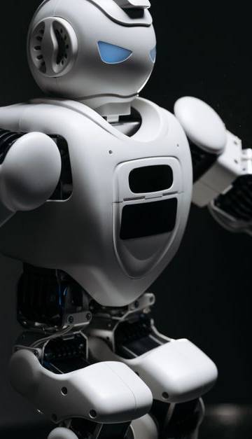 Close-up of a futuristic humanoid robot under dramatic lighting in dark ambiance.