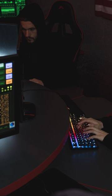 Cybersecurity professionals working on computer systems, focusing on data protection in a dimly lit room.