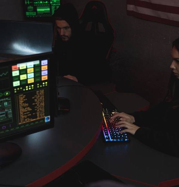 Cybersecurity professionals working on computer systems, focusing on data protection in a dimly lit room.