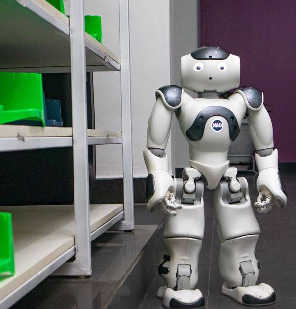 A humanoid robot standing in a modern corridor with shelves, representing futuristic technology.