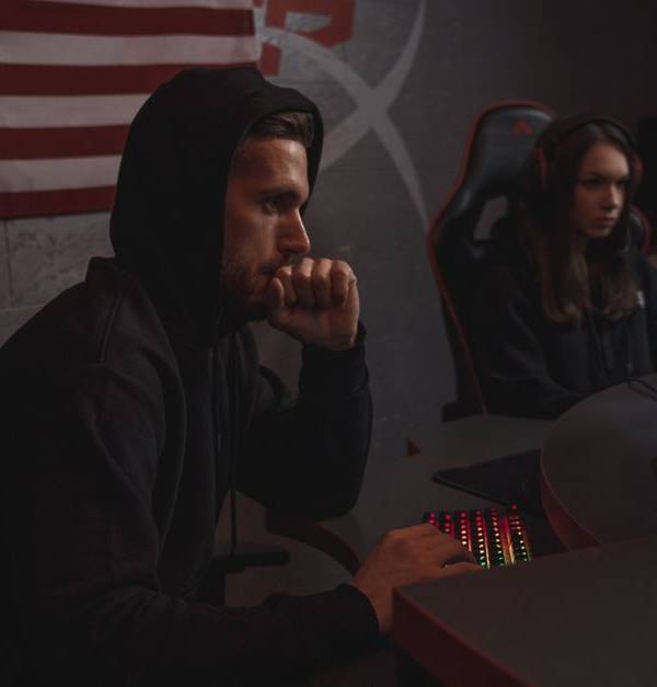 Two individuals analyze data in a dimly lit cybersecurity setting, highlighting digital defense themes.