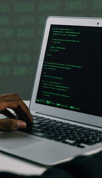 A focused adult working on a laptop demonstrates modern cybersecurity and coding skills indoors.