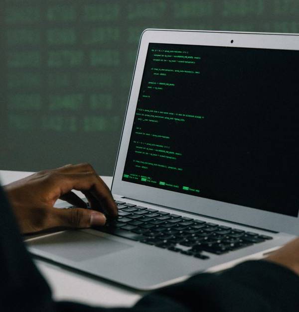 A focused adult working on a laptop demonstrates modern cybersecurity and coding skills indoors.