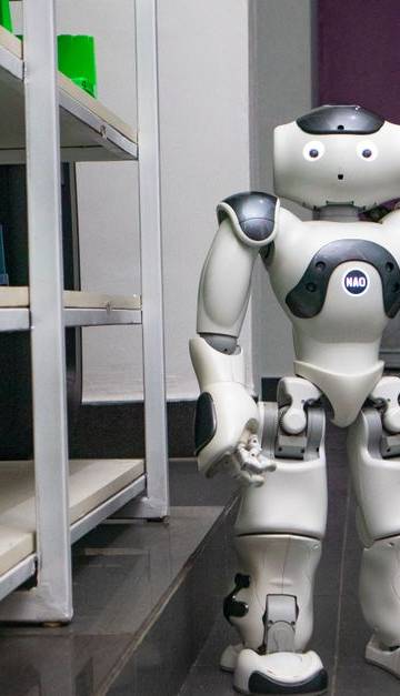 A humanoid robot standing in a modern corridor with shelves, representing futuristic technology.