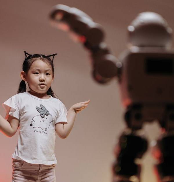 Child interacting with futuristic robot in a playful setting, showcasing modern technology.