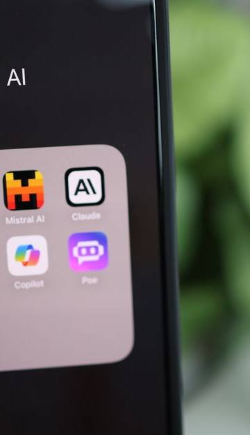 Close-up of a hand holding a smartphone with AI applications on screen.