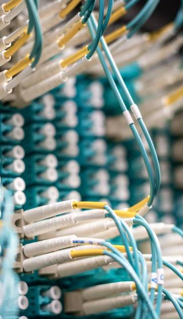 From below of fiber optic switch with sockets and connected rubber cables on blurred background