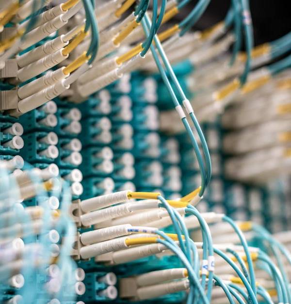 From below of fiber optic switch with sockets and connected rubber cables on blurred background