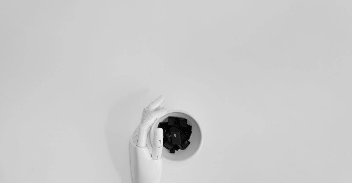 A robotic hand grasping black keyboard keys in a minimalist setting.