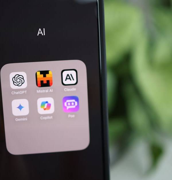 Close-up of a hand holding a smartphone with AI applications on screen.