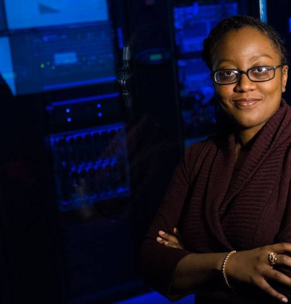 Professional woman standing confidently in a data center, surrounded by glowing servers.