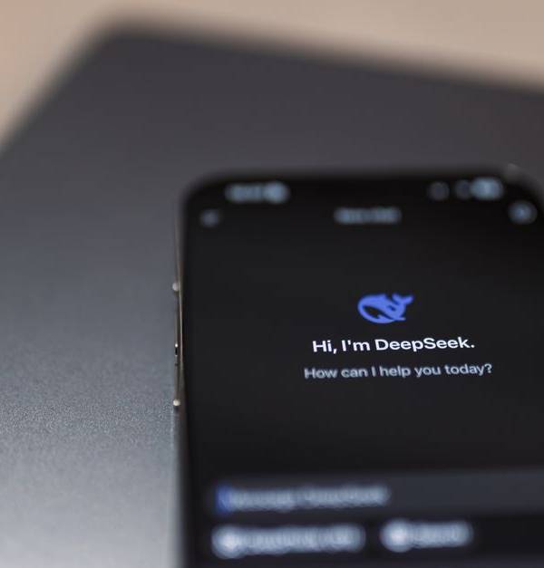 Close-up of a smartphone with AI assistant interface on screen over a laptop.