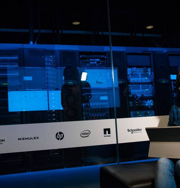 Woman using a laptop in a server room, showcasing modern technology and work environment.