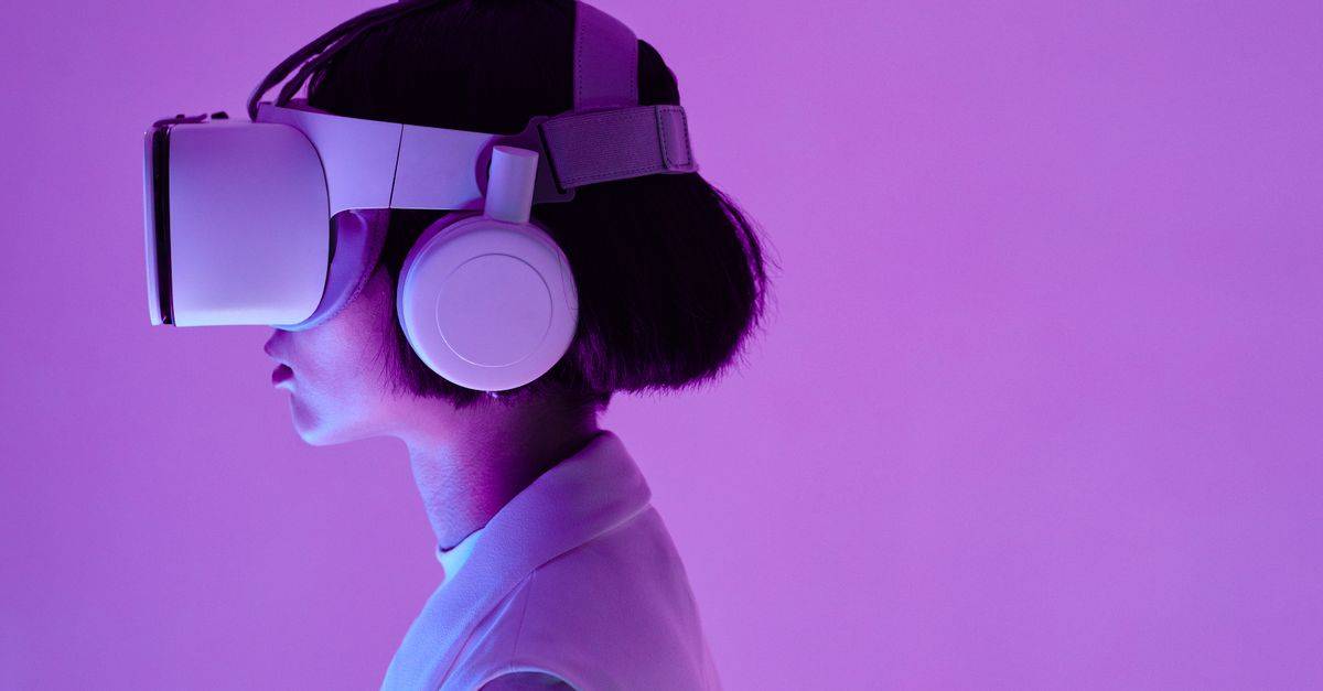 Side view of a woman wearing VR goggles in a purple-lit studio, highlighting modern technology.