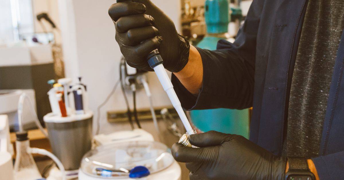 A lab technician performing an experiment with a pipette in a modern laboratory setting.