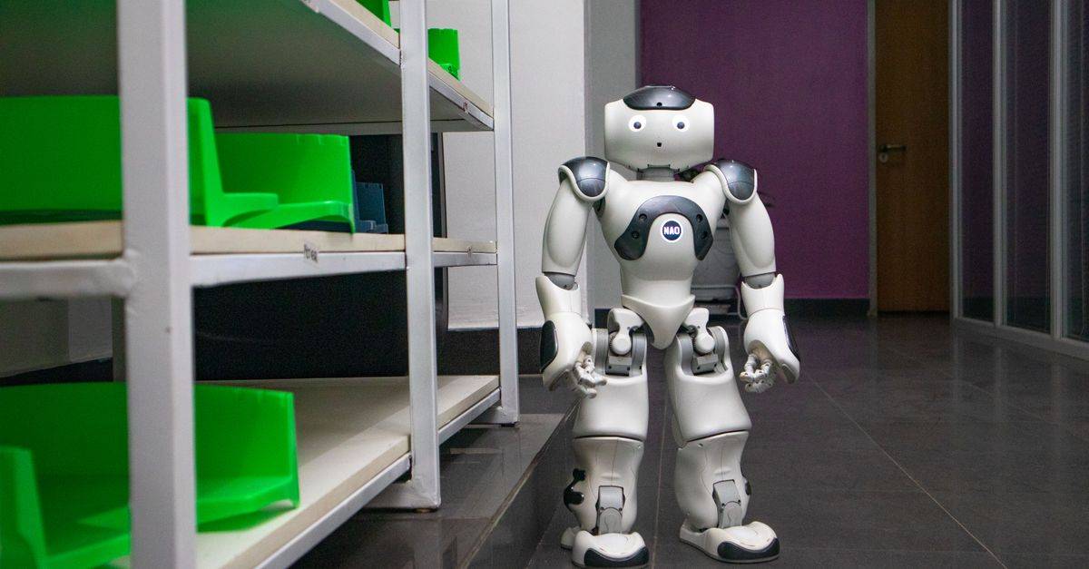 A humanoid robot standing in a modern corridor with shelves, representing futuristic technology.