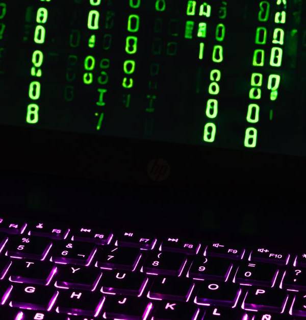 Illuminated laptop keyboard with Matrix-style green code cascading down screen.
