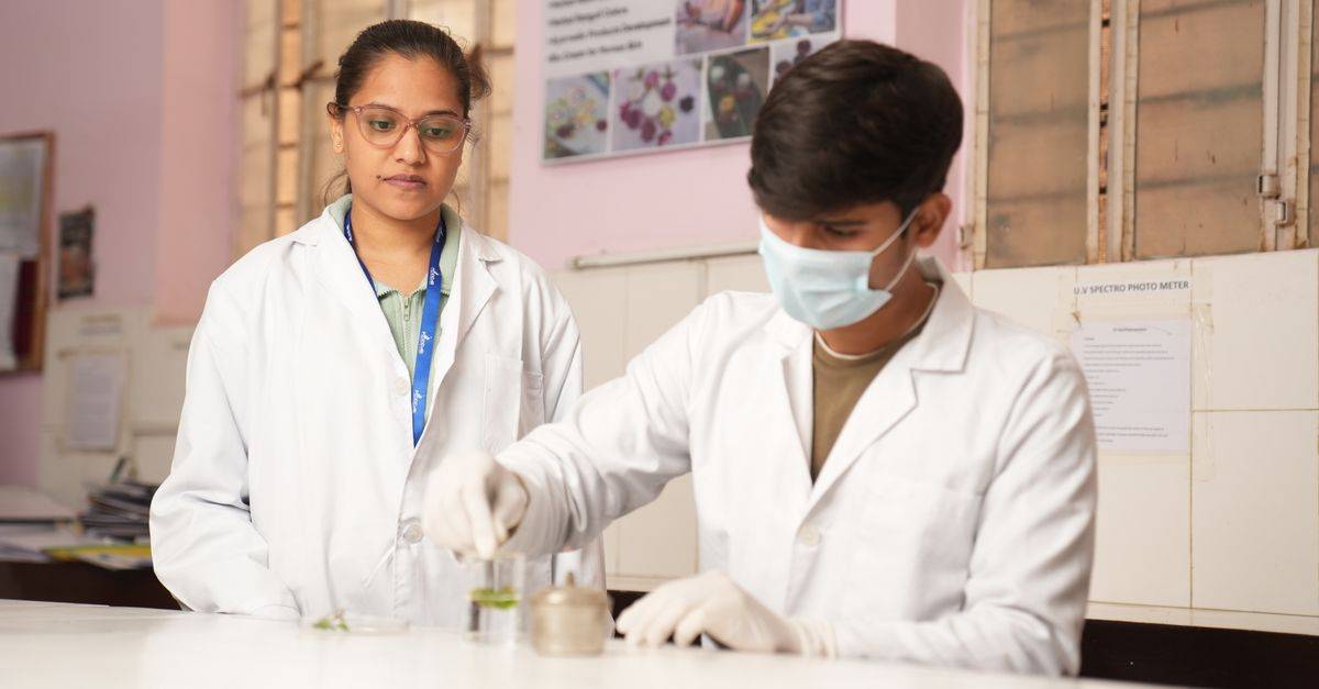 Two young scientists in lab coats performing an experiment in a laboratory setting.