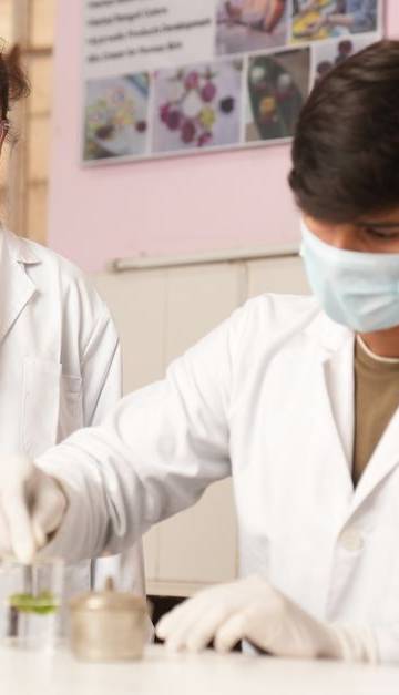 Two young scientists in lab coats performing an experiment in a laboratory setting.