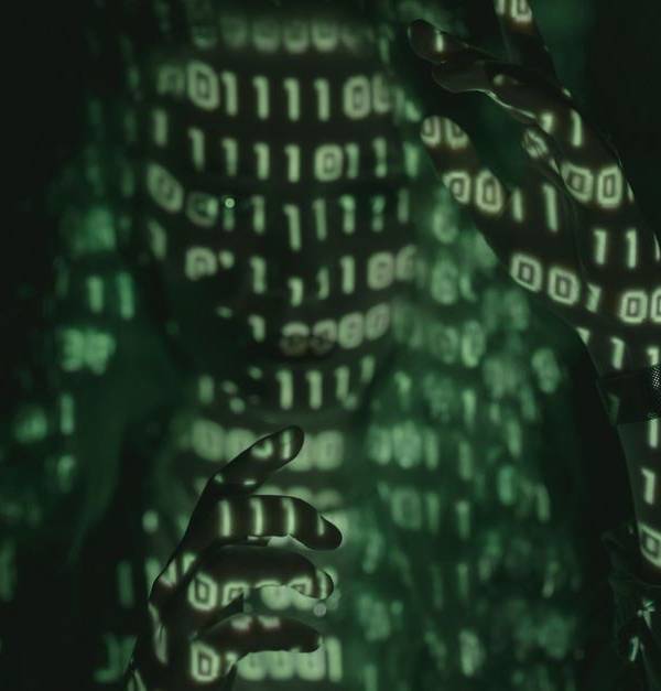 An unrecognizable person with binary code projected, symbolizing cybersecurity and digital coding.
