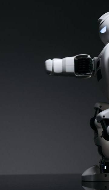 A white robot showcasing modern design on a sleek dark surface.
