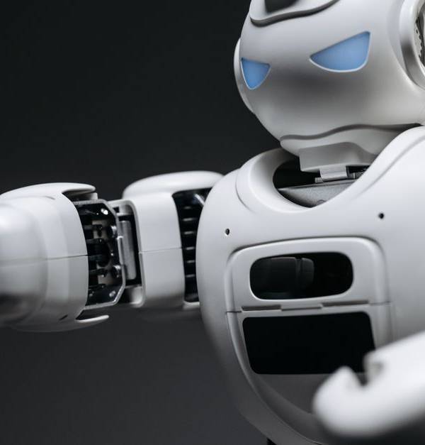 Detailed close-up of a high-tech white robot in a studio setting with a gray background.