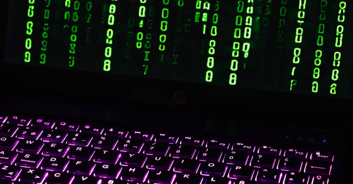 Illuminated laptop keyboard with Matrix-style green code cascading down screen.