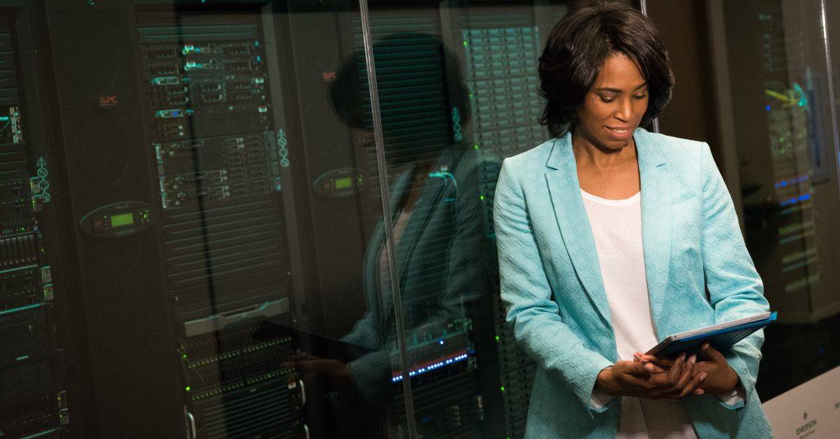 Female IT professional examining data servers in a modern data center setting.