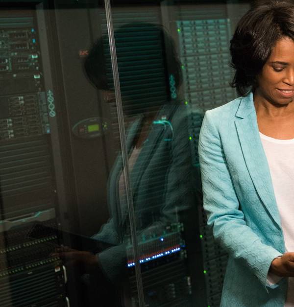 Female IT professional examining data servers in a modern data center setting.
