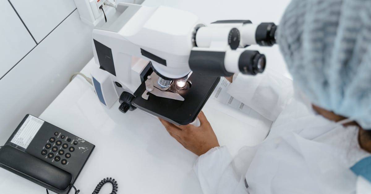 Scientist in lab coat observed using a microscope for research.