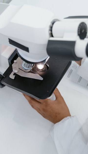 Scientist in lab coat observed using a microscope for research.