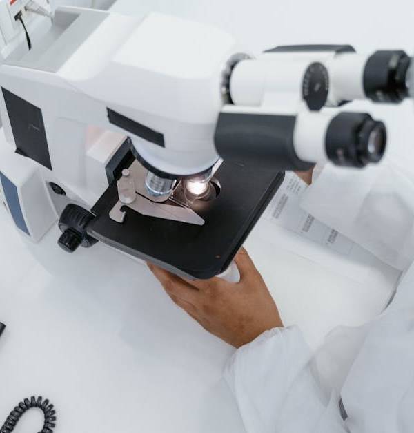Scientist in lab coat observed using a microscope for research.