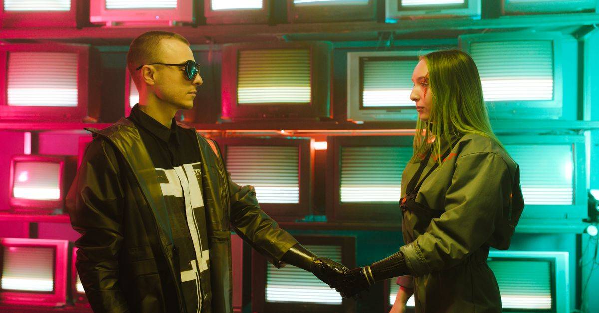 Two individuals with prosthetic arms engage in a handshake amidst a vibrant, retro television backdrop.