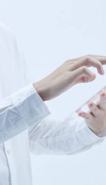 Person interacting with a transparent digital tablet, symbolizing technology and futurism.
