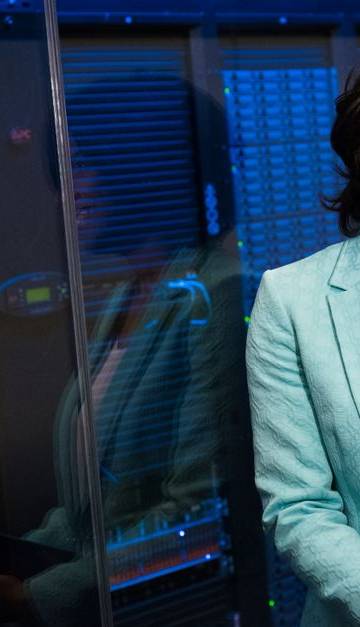 Smiling woman in data center showcasing technology expertise.