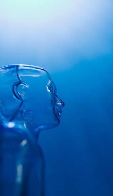 Transparent robotic figure illuminated by blue light, symbolizing AI and futuristic technology.