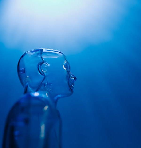 Transparent robotic figure illuminated by blue light, symbolizing AI and futuristic technology.