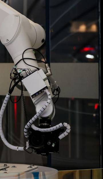 A white robotic arm operating indoors with a modern design and advanced technology.