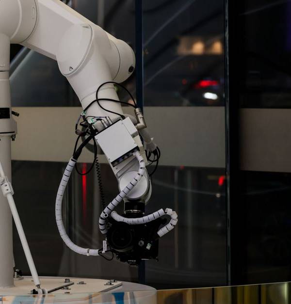 A white robotic arm operating indoors with a modern design and advanced technology.