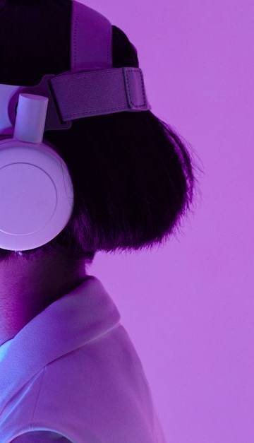 Side view of a woman wearing VR goggles in a purple-lit studio, highlighting modern technology.